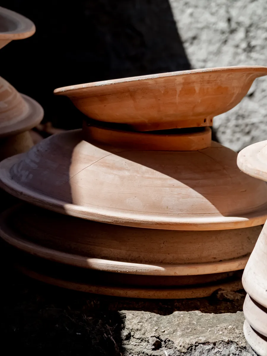 Stacked terracotta bowls in hard sunlight and deep shadow