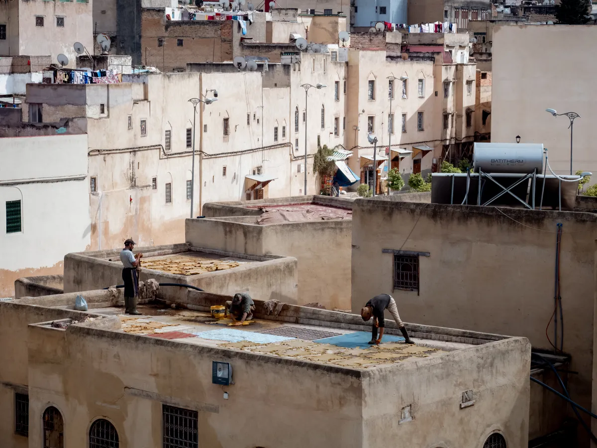 Workers on flat rooftops among pale old apartment buildings